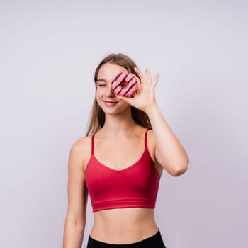 Young cute sport woman eating donut cake in studio background