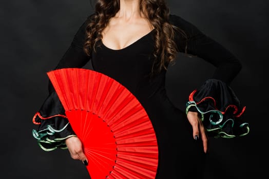 Portrait of beautiful young woman dancing flamenco with fan in studio