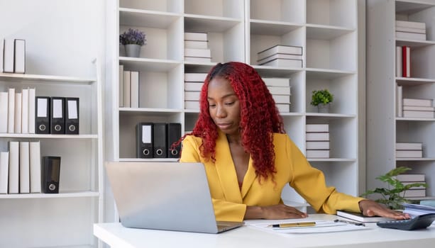 African American businesswoman is unhappy sitting on her office desk doing accounting and finance work..