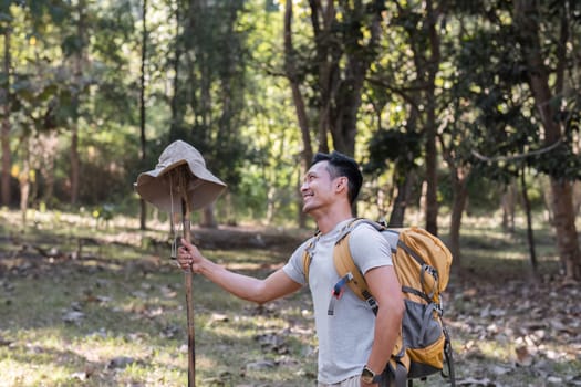 A middle-aged Asian tourist smiled happily. Backpacking in the national park Asian male tourist enjoying his hiking trip nature activities holiday outdoor activities.