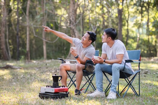 Asian LGBTQ couple drinking coffee in a romantic camping tent. LGBTQ couple drinking coffee in a camping tent, enjoying nature, forest, camping atmosphere, LGBTQ, gay, gay men..