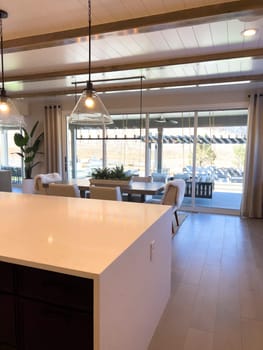 This modern kitchen showcases professional-grade stainless steel appliances, including a high-end gas range and double ovens, set against gray shaker cabinets and a marble backsplash. The warm wood flooring complements the cool tones of the cabinetry, creating an inviting culinary space.