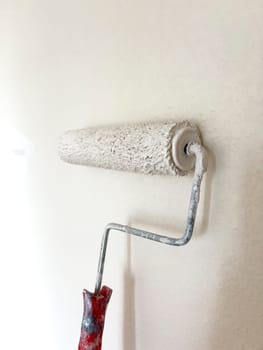 Detailed process of painting a wall, with a focus on a paint roller applying a fresh white coat, symbolizing the transformative power of a simple home improvement task.