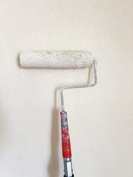 Detailed process of painting a wall, with a focus on a paint roller applying a fresh white coat, symbolizing the transformative power of a simple home improvement task.