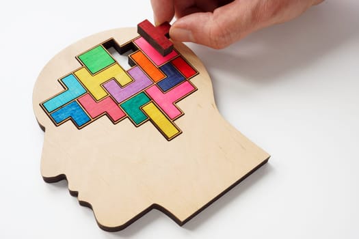 A hand inserts puzzle piece into the brain. Psychotherapy and psychology concept.