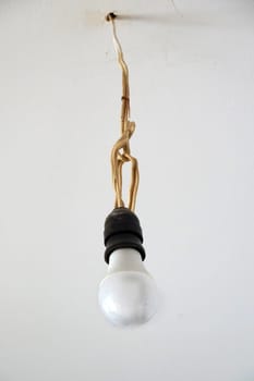 energy saving light bulb on an old wire hangs on the ceiling without a shade