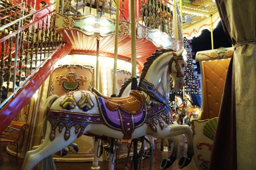 decorated white horse on a lighted children's carousel close-up