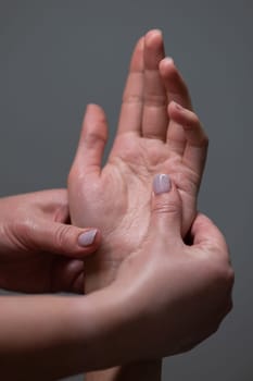 The masseuse massages the client's palms. Close-up of hands at a spa treatment. Vertical photo