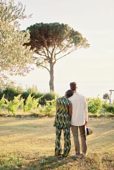 Woman rested her head on man shoulder while standing with him in a green garden. Back view. High quality photo