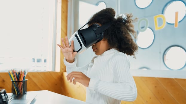 Creative girl wearing VR headset to learning in metaverse. Funny kid enjoy to wearing AI headset and enter to virtual world program in STEM technology class. Innovation. Future lifestyle. Erudition.