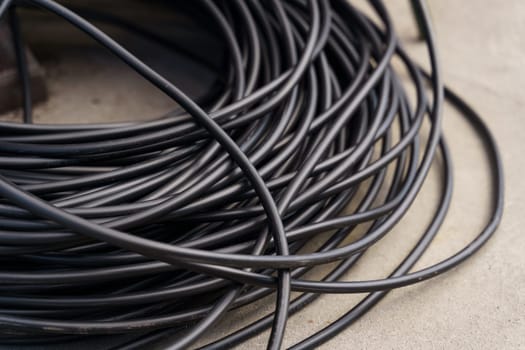 Numerous black wires laid out on top of a table in a disorderly fashion.