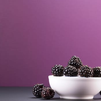 Bowl of blackberries on a purple background.