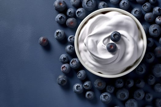 Bowl of yogurt with blueberries on a dark surface.