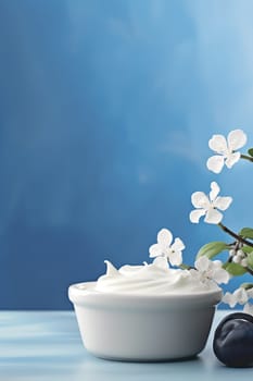 White cream in a bowl with flowers against a blue background.