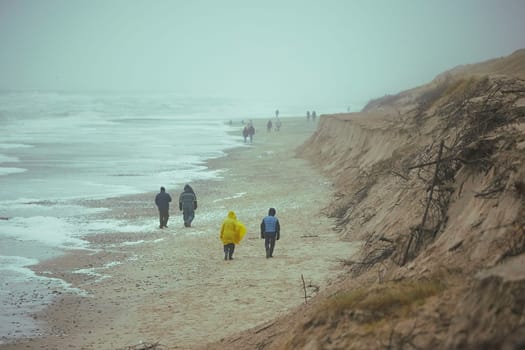 People walk on the beach in stormy weather in Sondervig Denmark.