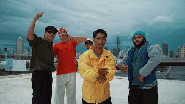 Skilled multicultural street dancing group pose at camera at roof top while moving to the rhyme and music. Young people or teenager moving to funky music, break dance. Outdoor sport 2024. Endeavor.