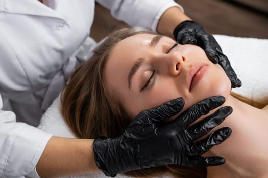 A gorgeous young woman undergoes a face lifting massage at the beauty clinic.