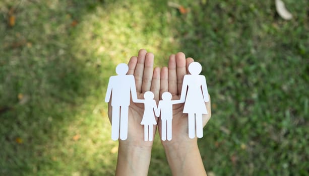 Background of paper family icon held in hand symbolize dedication to environmental friendly lifestyle of modern family, parenthood guiding sustainable lifestyle to their children. Gyre
