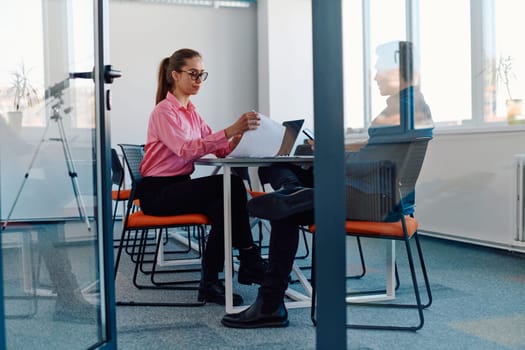 In a sleek, modern glass office, the director engages in a productive discussion with an employee, focusing on business projects and fostering collaboration.