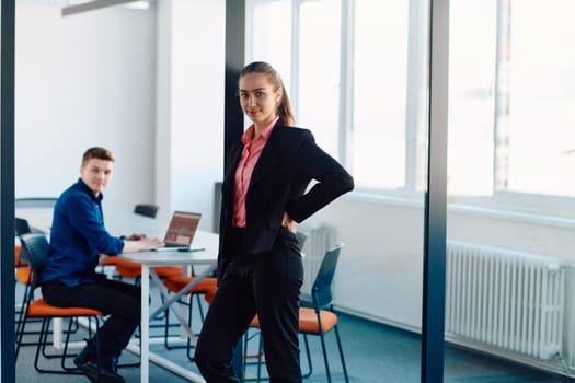 The director of an IT company poses with her colleague in a modern startup office setting.