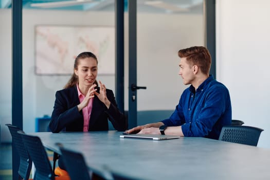 A business leader in a suit conversing with her worker in the IT industry about new business projects and existing business problems.