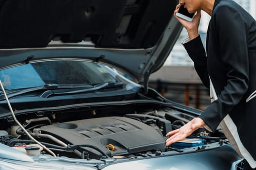 Young businesswoman whose car breakdown uses mobile phone to call for roadside assistance service. Travel and transportation vehicle problem. uds