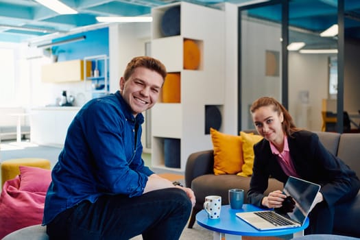 Multiethnic startup business team on meeting in a modern bright open space coworking office. Brainstorming, working on laptop. Group of coworkers walking around in motion blur.