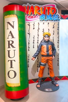 ikebukuro, japan - jan 16 2024: Life sized figurine featuring the manga hero of Naruto Shippuden aside a giant scroll at the entrance of the free exhibition of Naruto at the Anime Tokyo Station.