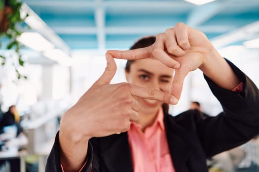 Closeup of hands, Smiling Business Woman Making Frame Gesture with at modern bright coworking open space startup office.