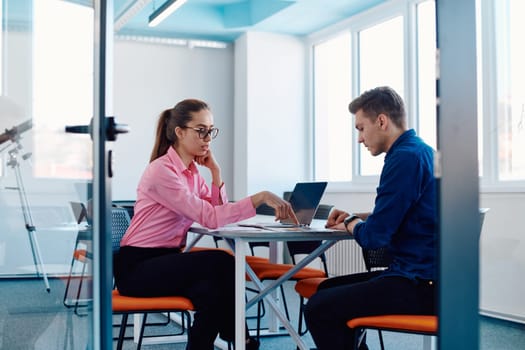 In a sleek, modern glass office, the director engages in a productive discussion with an employee, focusing on business projects and fostering collaboration.