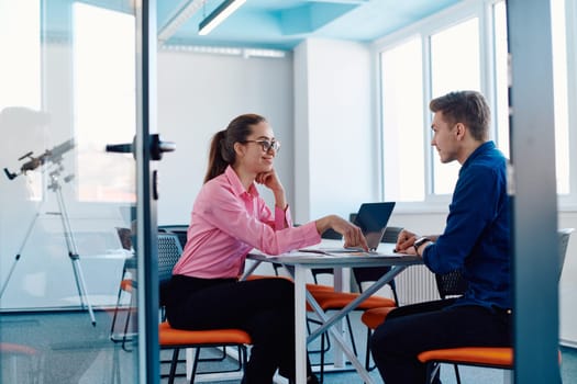 In a sleek, modern glass office, the director engages in a productive discussion with an employee, focusing on business projects and fostering collaboration.