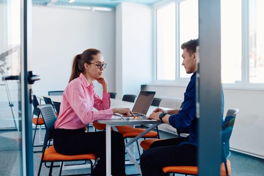 In a sleek, modern glass office, the director engages in a productive discussion with an employee, focusing on business projects and fostering collaboration.