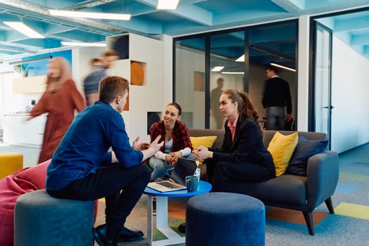 Multiethnic startup business team on meeting in a modern bright open space coworking office. Brainstorming, working on laptop. Group of coworkers walking around in motion blur.