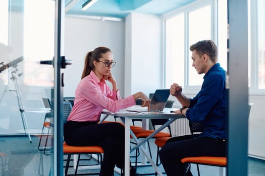 In a sleek, modern glass office, the director engages in a productive discussion with an employee, focusing on business projects and fostering collaboration.