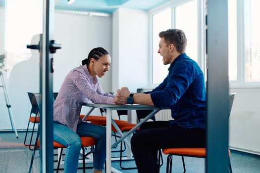 In a modern startup office, a businessman and a businesswoman business colleagues engage in a symbolic arm-wrestling match, reflecting teamwork, competition, and innovation in their dynamic workplace