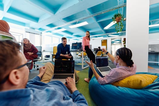 In a modern startup office, a diverse group of young and capable businesspeople engage in lively discussions about various projects, showcasing teamwork, innovation, and entrepreneurial spirit.