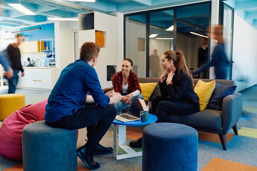 Multiethnic startup business team on meeting in a modern bright open space coworking office. Brainstorming, working on laptop. Group of coworkers walking around in motion blur.