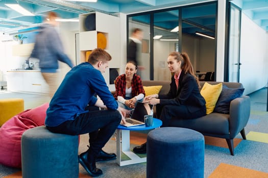 Multiethnic startup business team on meeting in a modern bright open space coworking office. Brainstorming, working on laptop. Group of coworkers walking around in motion blur.