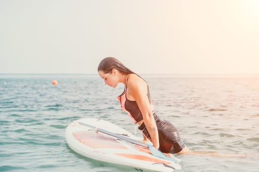 Silhouette of woman standing, surfing on SUP board, confident paddling through water surface. Idyllic sunset or sunrise. Sports active lifestyle at sea or river.