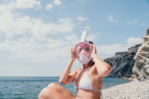 Young happy woman in white bikini put pink snorkeling mask on beach before swimming. girl having fun relaxing on beautiful beach. Beach lifestyle