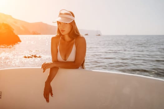 Close up shot of happy young caucasian woman looking at camera and smiling. Cute woman portrait in bikini posing on a volcanic rock high above the sea