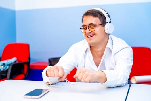 Man with down syndrome dancing sitting while listening to music using headphones and mobile