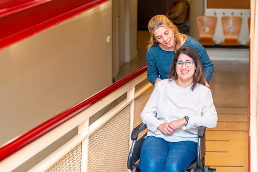 Woman walking a mental disabled woman in wheelchair along a day care center