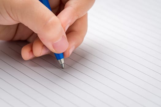 Little girl starts writing on a lined notebook with a ballpoint pen