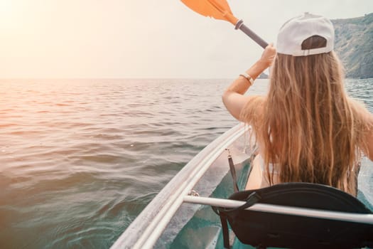 Woman in kayak back view. Happy young woman with long hair floating in transparent kayak on the crystal clear sea. Summer holiday vacation and cheerful female people having fun on the boat.