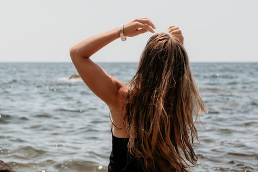 Woman travel sea. Young Happy woman in a long red dress posing on a beach near the sea on background of volcanic rocks, like in Iceland, sharing travel adventure journey