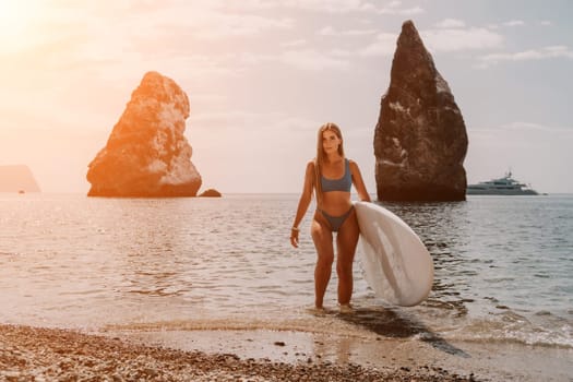 Close up shot of beautiful young caucasian woman with black hair and freckles looking at camera and smiling. Cute woman portrait in a pink bikini posing on a volcanic rock high above the sea