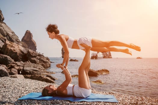 Woman sea yoga. Back view of free calm happy satisfied woman with long hair standing on top rock with yoga position against of sky by the sea. Healthy lifestyle outdoors in nature, fitness concept.