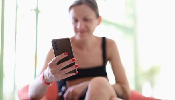 Smiling woman holding smartphone and looking at positive information. Cheerful message in social networks and chats