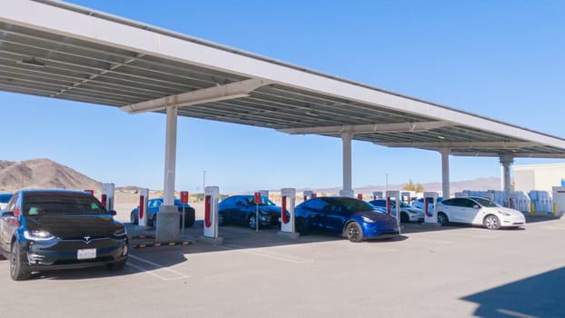 Baker, California, USA-December 3, 2022-During the day, a Tesla vehicle is seen charging at a Tesla Supercharging station, utilizing the high-speed charging infrastructure for convenient and efficient electric vehicle refueling.